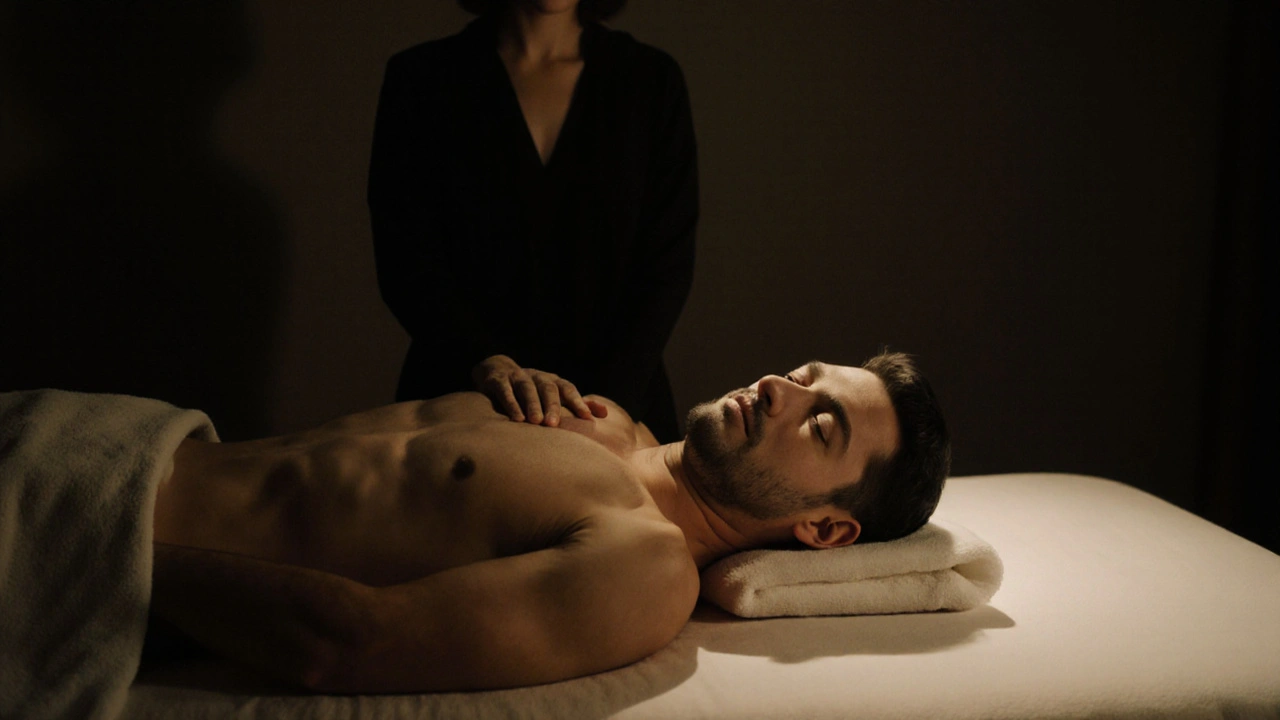 Man liggend op een massagebed met een warme doek op zijn rug, vrouw in de schaduw achter hem, stilte en herstel.